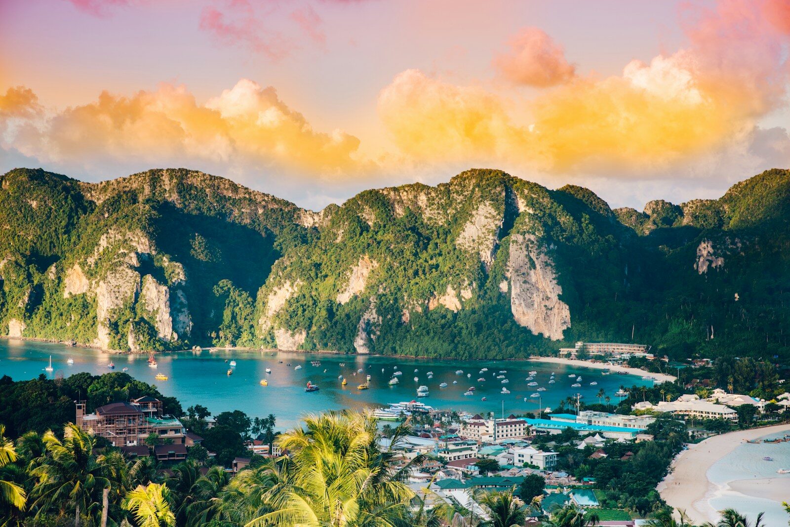 Longtail boats anchored in a bay on Phi Phi Island, Thailand, beneath green mountains